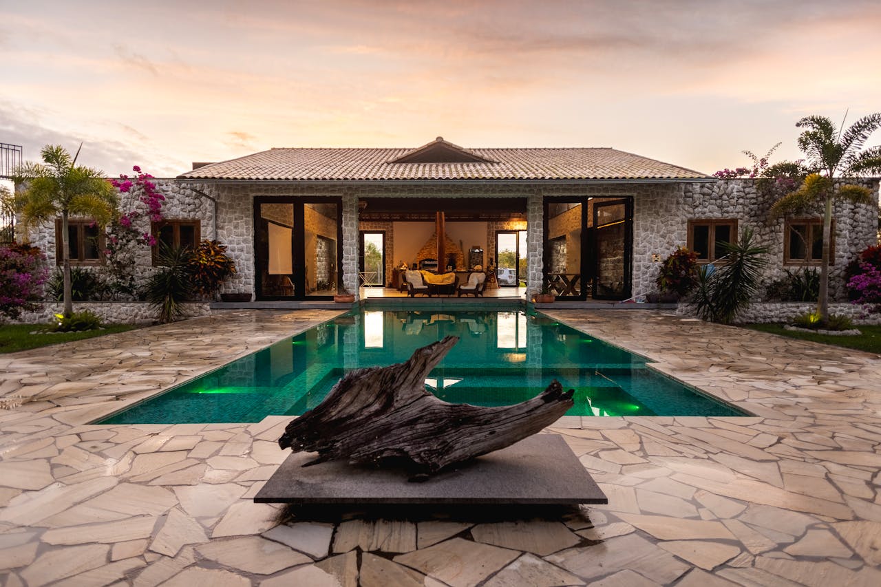 The Art of Drawing Readers In: Your attractive post title goes here Elegant villa with a pool, stone facade, and tropical garden at sunset.